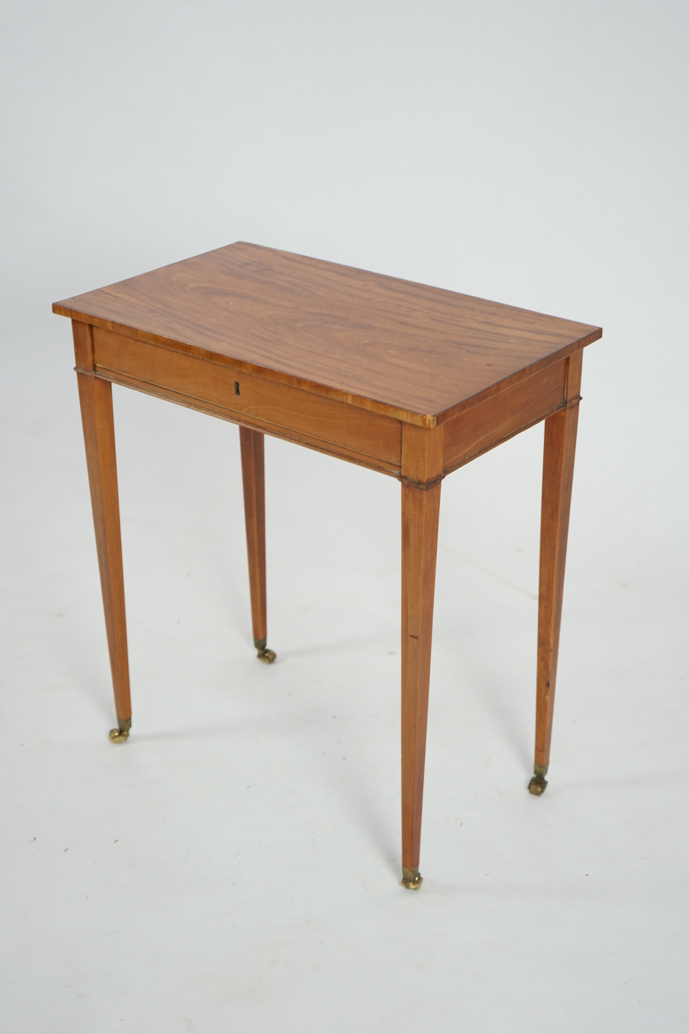 An Edwardian satinwood occasional table, with rectangular top and frieze drawer, on square tapered legs, fitted brass castors, 62cm wide, 37cm deep, 71cm high. Condition - of good rich colour, some old scuffs and scratch